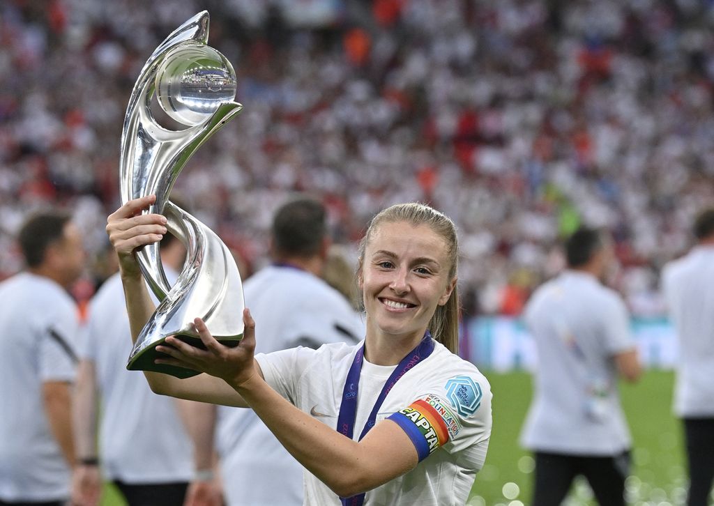 England's midfielder Leah Williamson poses with the trophy as England players celebrate after their win in the UEFA Women's Euro 2022 final football match between England and Germany at the Wembley stadium, in London, on July 31, 2022. - England won a major women's tournament for the first time as Chloe Kelly's extra-time goal secured a 2-1 victory over Germany at a sold out Wembley on Sunday.
