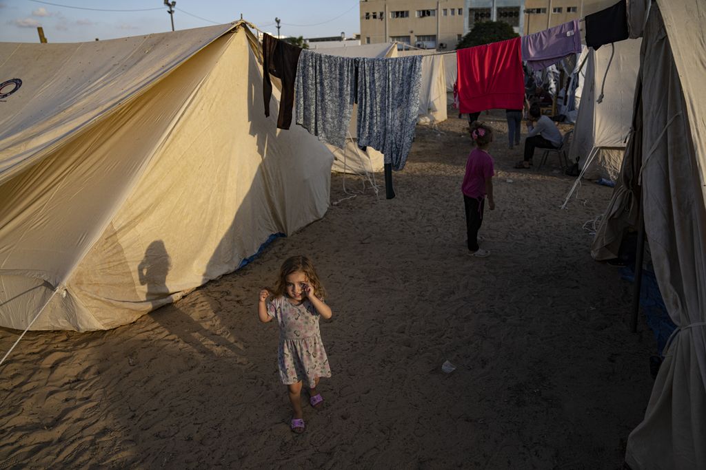 Anak-anak Palestina yang mengungsi akibat pengeboman Israel di Jalur Gaza berjalan diantar tenda di kamp pengungsian yang disediakan UNDP di Khan Younis, Kamis (19/10/2023). 