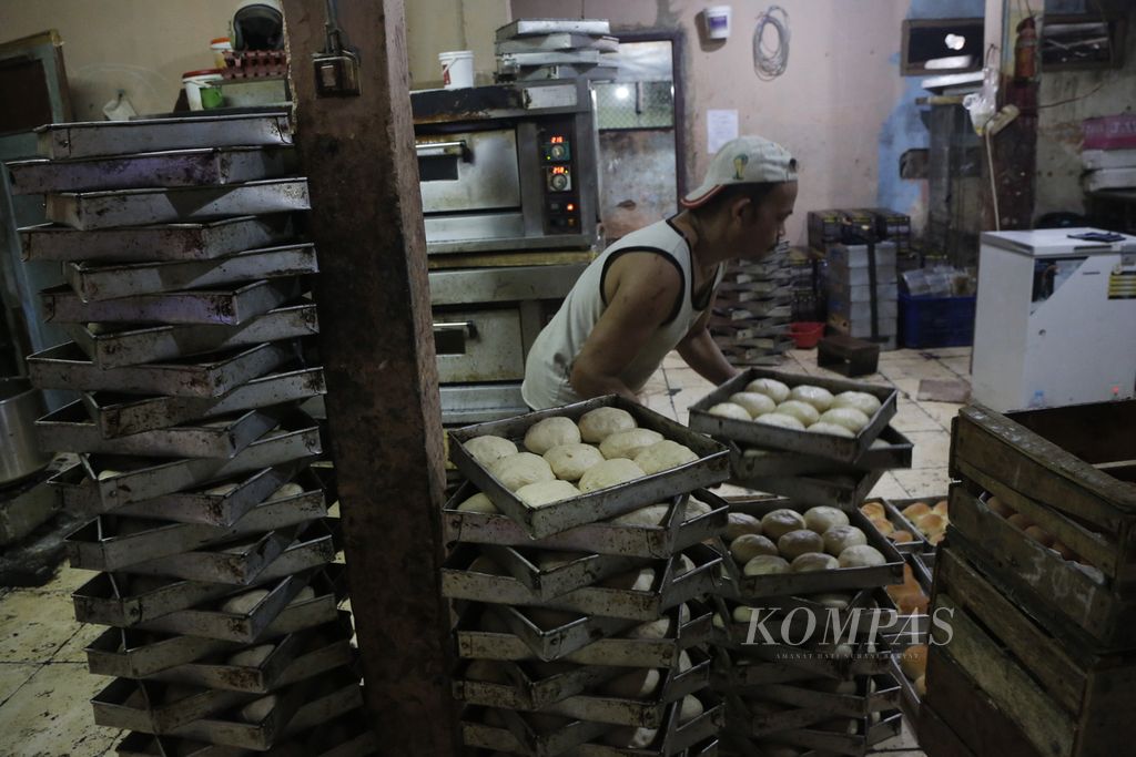 Pekerja mengangkat roti untuk dimasukkan ke dalam oven di sebuah UMKM pembuatan roti di kawasan Bendungan Hilir, Jakarta Pusat, Selasa (14/3/2023).