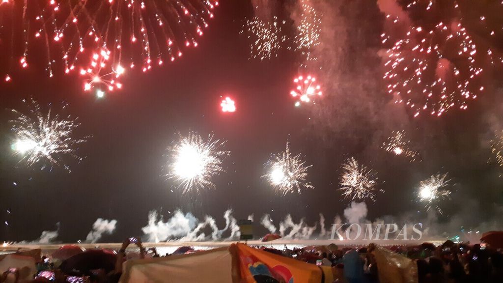 Ratusan pengunjung Ancol mengabadikan pesta kembang api saat malam pergantian tahun, Selasa (31/12/2019). Di tengah hujan deras dan badai, pengunjung memilih bertahan demi dapat menyaksikan pertunjukan kembang api.
