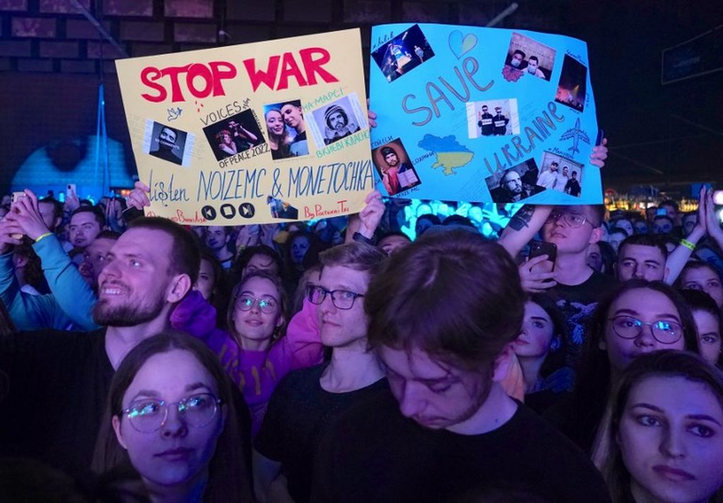 Para penggemar mengangkat poster menentang perang Rusia di Ukraina selama konser anti-perang yang dibawakan musisi Rusia yang diikuti lebih dari seribu penggemar, terutama warga Ukraina dan Belarus, di Warsawa, Polandia, pada 21 April 2022. 