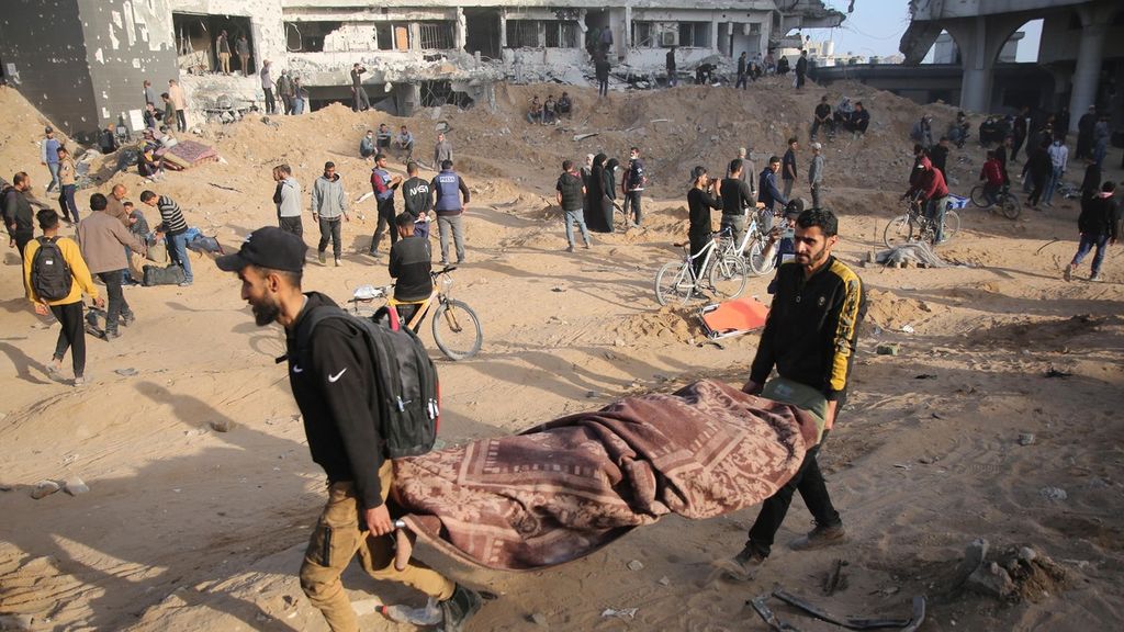 Warga Palestina membawa jenazah yang tertutup ketika warga berkumpul untuk memeriksa kerusakan di Rumah Sakit Al-Shifa di Gaza setelah militer Israel mundur dari kompleks perumahan rumah sakit tersebut pada 1 April 2024, di tengah pertempuran yang sedang berlangsung antara Israel dan kelompok militan Hamas.