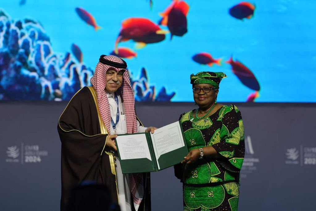 Direktur Jenderal Organisasi Perdagangan Dunia (WTO) Ngozi Okonjo-Iweala serta Menteri Perdagangan dan Investasi Arab Saudi Majid al-Qasabi berfoto dengan dokumen yang ditandatangani pada sesi tentang Subsidi Perikanan pada Konferensi Tingkat Menteri WTO ke-13 di Abu Dhabi, Uni Emirat Arab (UEA),  pada 26 Februari 2024.  