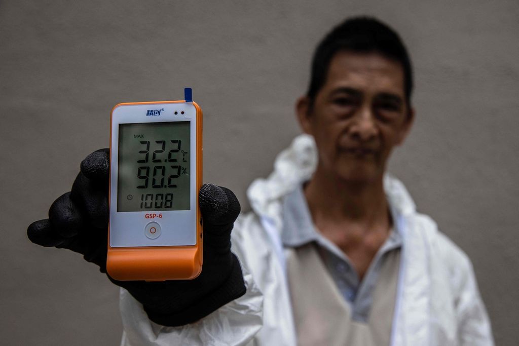 Seorang pekerja memperlihatkan suhu yang tercatat di perlengkapan alat pelindung diri di Hong Kong, 1 Agustus 2023. 
