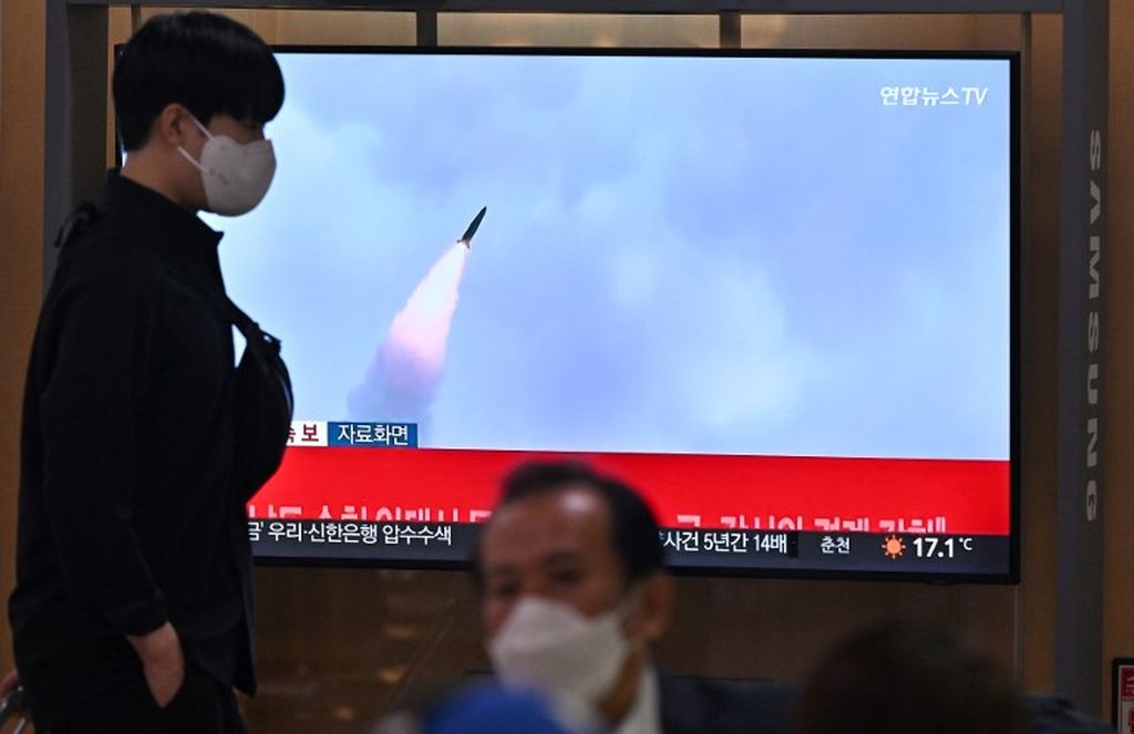 Seorang pria berjalan melewati layar televisi yang menayangkan siaran berita dengan rekaman dokumentasi uji coba rudal Korea Utara, di sebuah stasiun kereta api di Seoul, 29 September 2022.