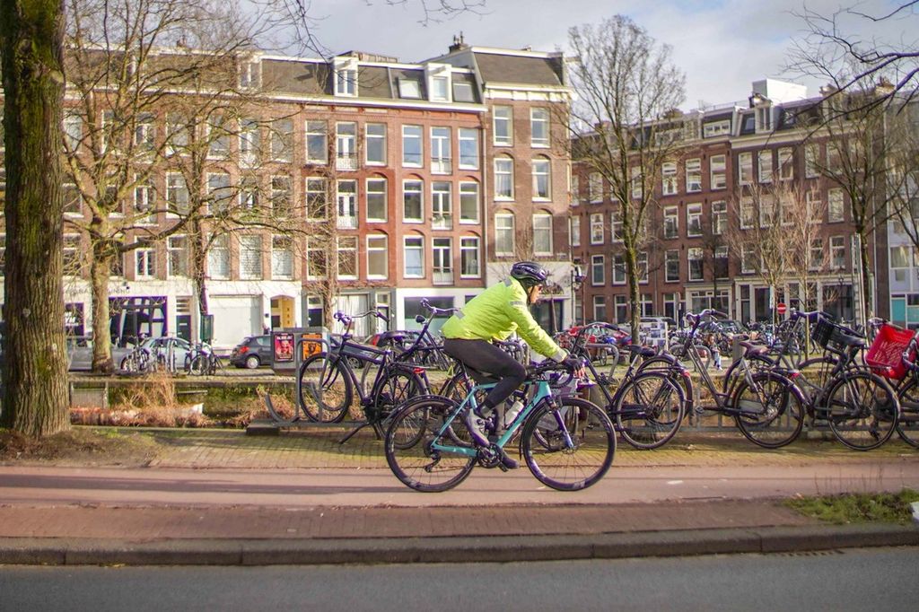 Royke bersepeda di tengah kota Amsterdam dengan pemandangan ratusan sepeda terparkir di pinggir kanal.
