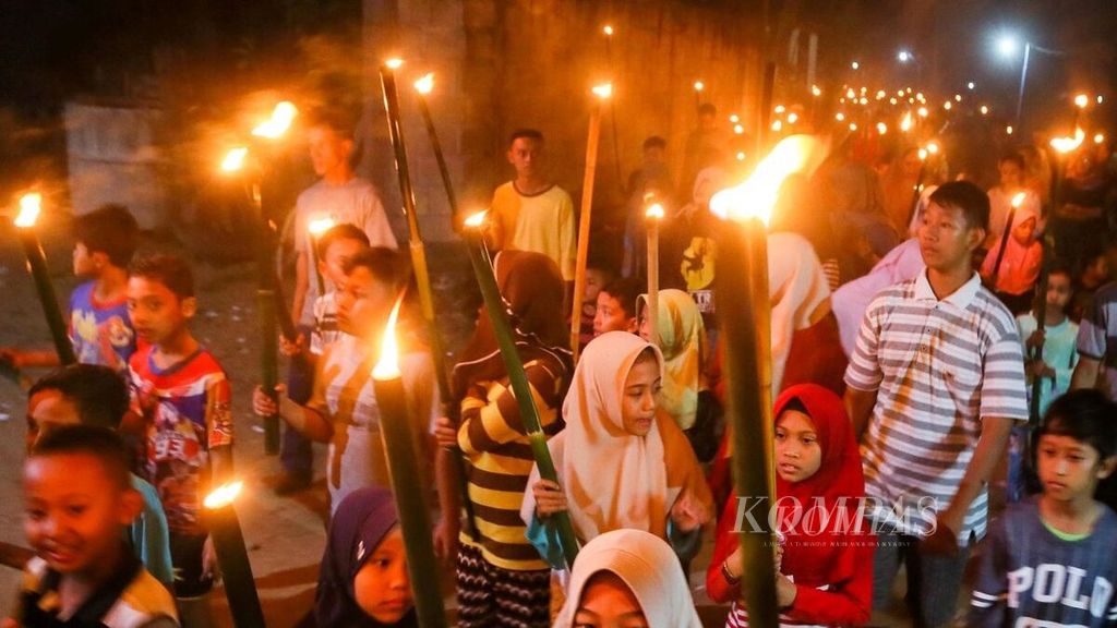 Children mingle with residents as they walk around the village carrying torches while reciting takbeer during the night of takbeer in Sukoharjo, Pacitan, East Java, on Tuesday (4/6/2019).