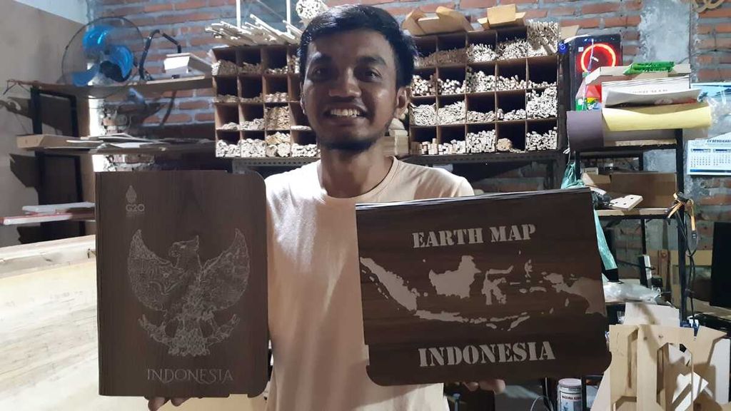 Muhammad Aliyafi (29) menunjukkan tempat buku atau binder bergambar burung Garuda di bengkel kerja Hucravindo, salah satu Industri kecil menengah kerajinan kayu di Sidoarjo, Jawa Timur, Senin (7/11/2022). 