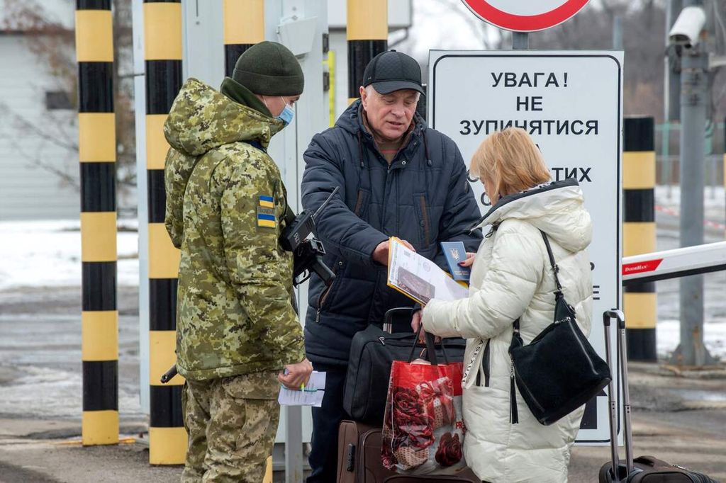 A Ukrainian frontier guard checks documents of people crossing the check point at Ukrainian-Russian border, some 40 km from the second largest Ukrainian city of Kharkiv, on February 16, 2022. 