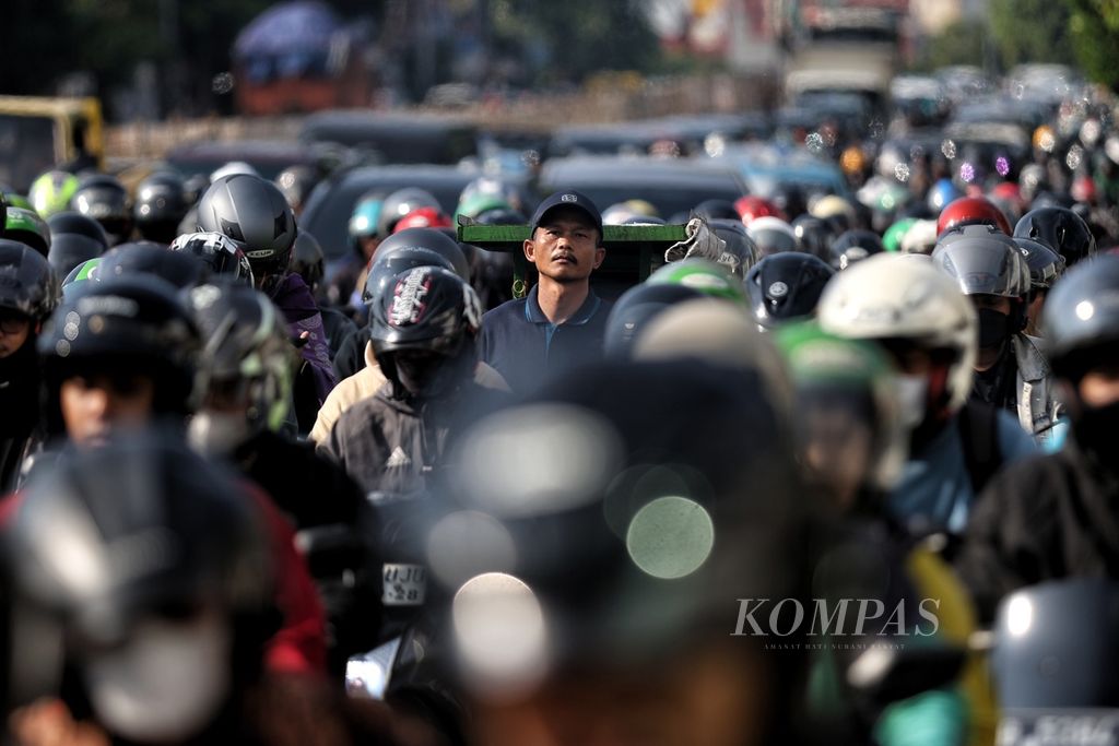 Traders were stuck in traffic while pulling their carts on Mampang Prapatan Street, Jakarta, on Friday (19/4/2024). The congestion was partly caused by firefighting activities at the Saudara picture frame store, which was engulfed in flames and claimed the lives of seven people.
