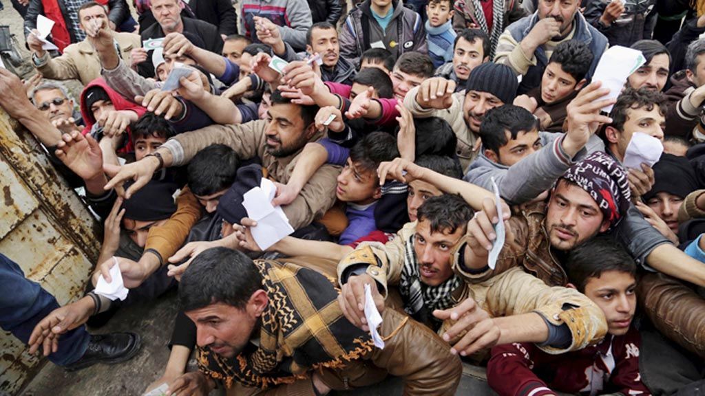 Warga Irak  menyodorkan kupon untuk memperoleh bantuan pangan yang didistribusikan Bulan Sabit Merah Irak di Mosul timur, Irak, Selasa (31/1). Pasukan Pemerintah Irak menyatakan, separuh wilayah Mosul di bagian timur telah dibebaskan dari milisi Negara Islam di Irak dan Suriah (NIIS).
