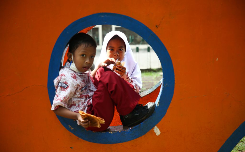 Siswa sekolah dasar menikmati jajanan sambil bermain di taman saat pulang sekolah di Joglo, Kembangan, Jakarta Barat, Kamis (27/1/2021). Meski siswa usia 6 tahun ke atas telah mendapat vaksin Covid-19, tetap dibutuhkan kedisiplinan menerapkan 3M, yaitu mengenakan masker, menjaga jarak, serta mencuci tangan.