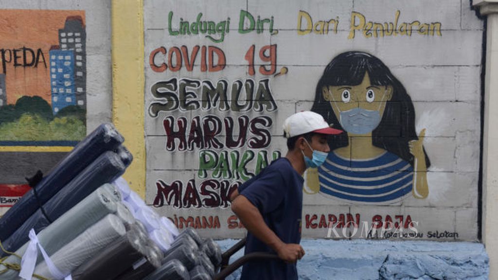 Warga melintasi mural yang dibuat untuk meningkatkan kewaspadaan masyarakat akan bahaya Covid-19 di Kelurahan Kota Bambu Selatan, Palmerah, Jakarta Barat, Jumat (7/2/2021). Pemerintah akhirnya menarik rem darurat merespons lonjakan Covid-19 dengan menerapkan Pemberlakuan Pembatasan Kegiatan Masyarakat (PPKM) darurat, 3-20 Juli 2021. Melalui PPKM darurat diharapkan kasus Covid-19 bisa terkendali dan menekan penyebaran varian baru virus korona yang begitu cepat.