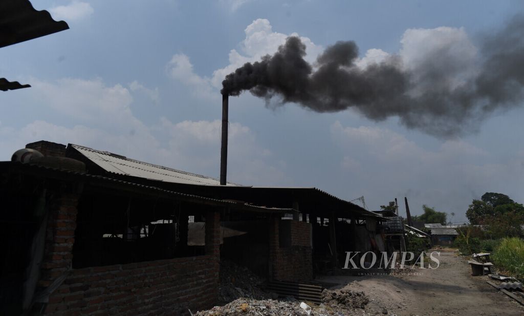 Asap hitam keluar dari cerobong asap di sentra pembuatan tahu dengan bahan bakar plastik impor di Desa Tropodo, Kecamatan Krian, Sidoarjo, Jawa Timur, Selasa (26/11/2019). 