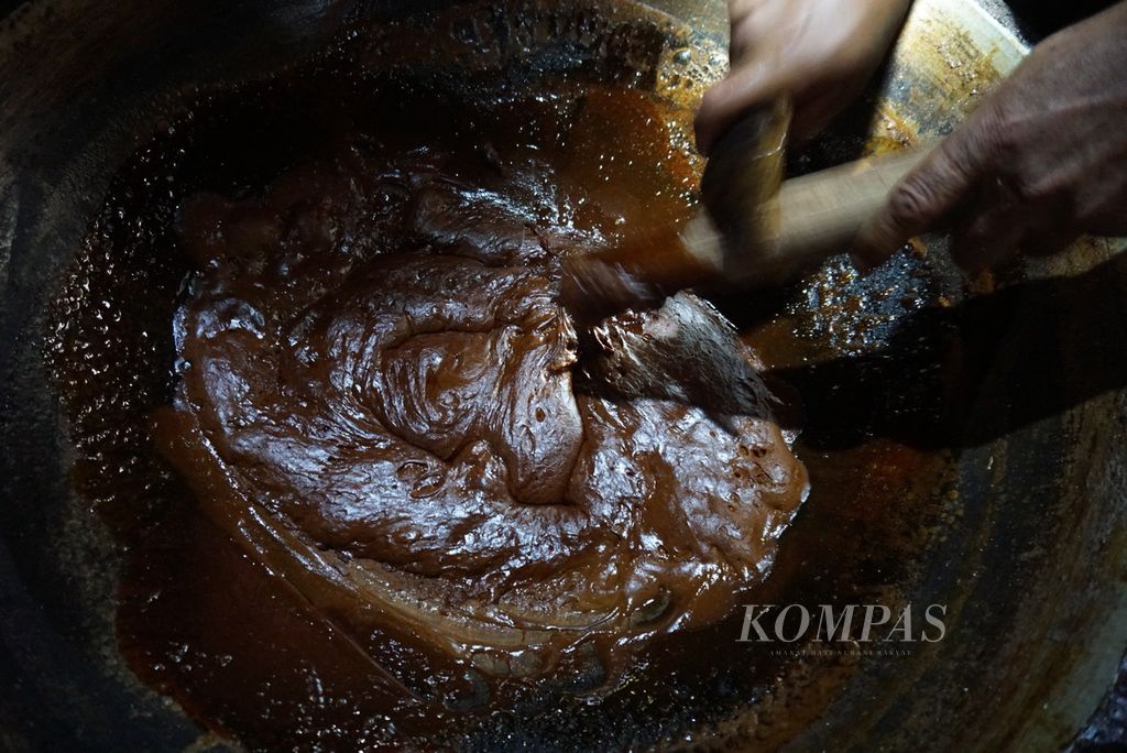 Hendrik Bonde, seorang petani gula aren, mengaduk adonan nira yang telah mengental dalam proses pembuatan gula semut, Selasa (19/7/2022), di Desa Tapa Aog, Lolayan, Bolaang Mongondow, Sulawesi Utara.
