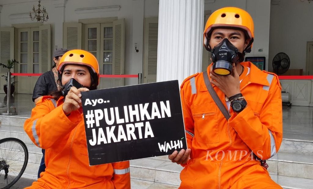 Dua orang yang tergabung dalam Gerakan Inisiatif Bersihkan Udara Koalisi Semesta (Ibu Kota) menunjukkan papan informasi untuk mendorong kualitas udara yang baik di Jakarta di depan Gedung Balai Kota DKI Jakarta, Rabu (5/12/2018).
