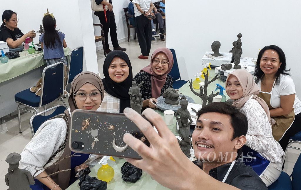 Participants in a sculpture, painting and engraving workshop take selfies after completing their work at the National Gallery, Jakarta, Saturday (27/7/2024).