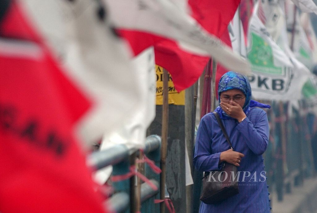 Seorang pejalan kaki melintas di deretan bendera partai politik peserta Pemilihan Umum 2004 yang dipasang di pagar pembatas jalan depan Stasiun Kereta Api Kota, Jakarta Barat (12/3). Sebanyak 141 caleg akan memperebutkan suara di Jakarta Barat, Jakarta Utara, dan Kepulauan Seribu (dapil DKI Jakarta 3).