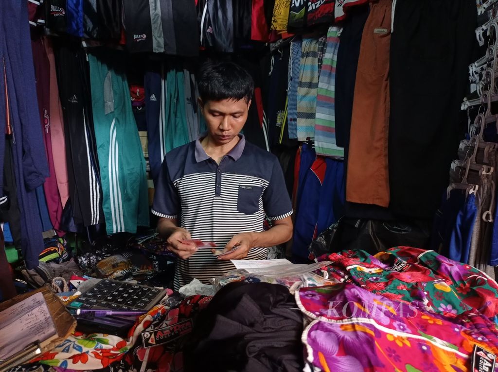 Nanang Sopian (36), salah satu pedagang di Pasar Cipulir, Jakarta, tengah memeriksa nota belanja pada Selasa (29/3/2022).
