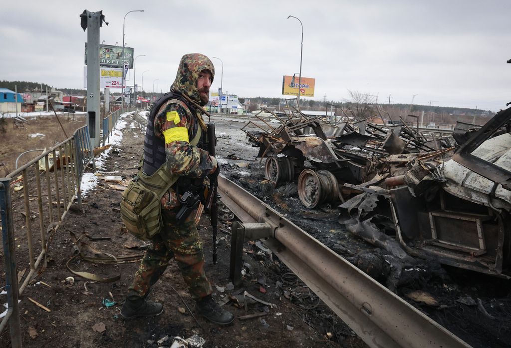 Seorang tentara berjaga di dekat sisa kendaraan militer Rusia yang hancur di Bucha, dekat Kiev, Ukraina, 1 Maret 2022.