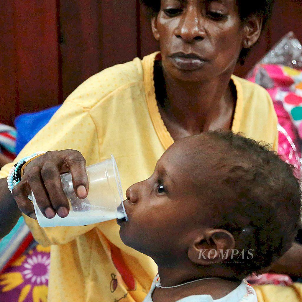 Seorang ibu memberikan susu kepada anaknya yang dirawat di Rumah Sakit Umum Daerah Agats, Kabupaten Asmat, Papua, yang ditempatkan di aula Gereja Kristen Indonesia Klasis Asmat, Minggu (21/1). Hingga Minggu malam, 43 pasien anak-anak dengan gizi buruk dirawat di aula tersebut.