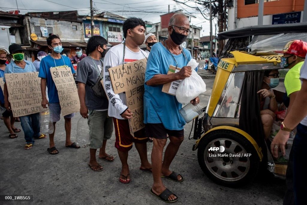 Para sopir angkutan kota menggunakan masker antre untuk menerima bantuan makanan dari seorang warga di Kota Manila, Filipina, 6 Agustus 2020. Filipina jatuh dalam resesi setelah mengalami kontraksi terbesar triwulanan sebagaimana ditunjukkan data per 6 Agustus 2022.  (Photo by Lisa Marie David / AFP)