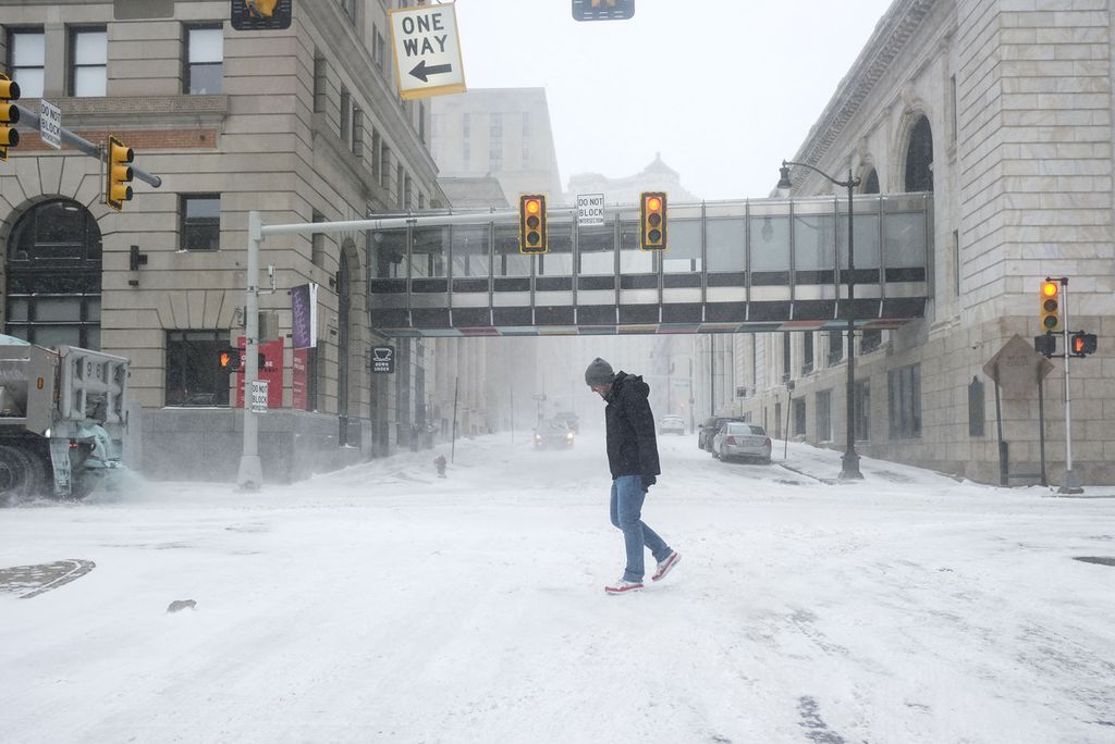 Seorang penduduk Detroit dengan berjalan di jalan yang tertutup salju di Detroit, Jumat (23/12/2022).