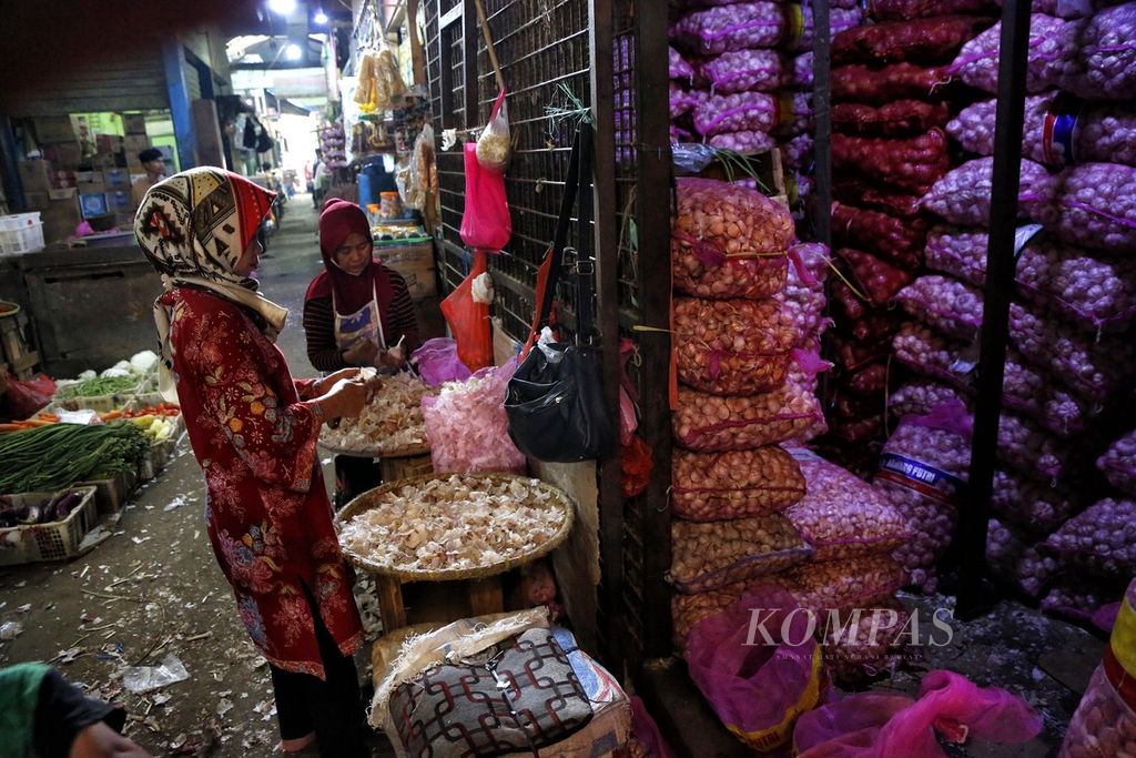 Buruh membersihkan kulit dan batang bawang putih impor di Pasar Induk Kramatjati, Jakarta Timur, Minggu (28/5/2023). 