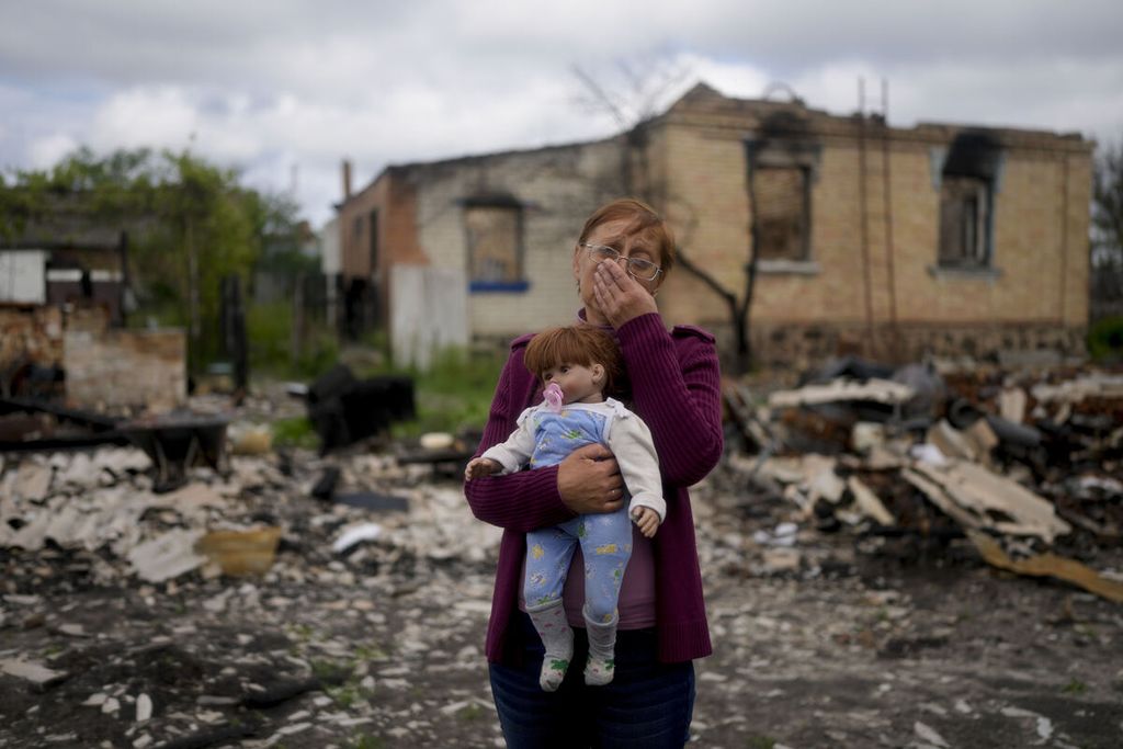 Nila Zelinska menggendong boneka cucunya yang dia temukan di tengah puing-puing rumahnya yang hancur saat terjadi serangan Rusia di Potashnya, pinggiran Kyiv, Ukraina, 31 Mei 2022. 