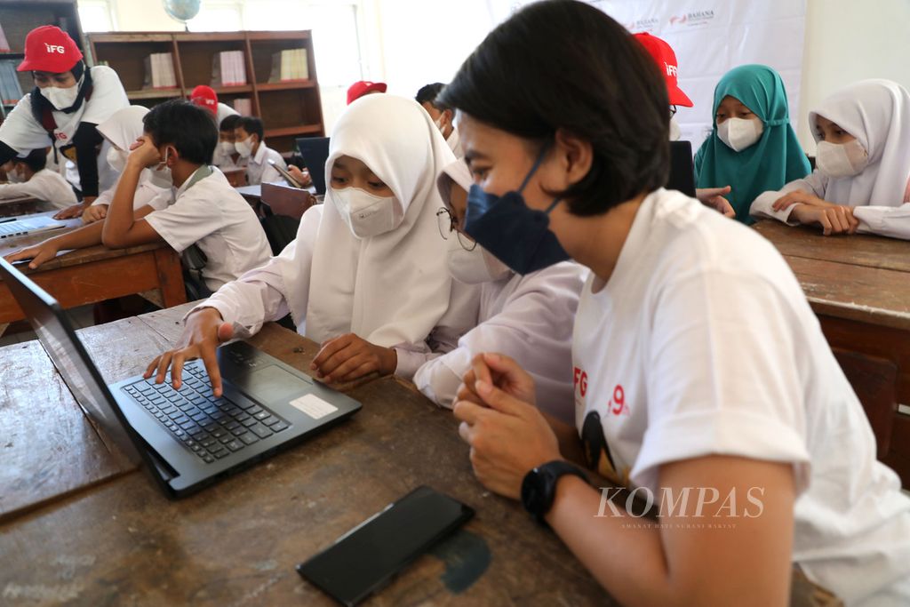 Relawan dari Indonesia Financial Group (IFG) mendampingi siswa SD Negeri 01 Malasari dalam mengoperasikan komputer jinjing atau laptop di Desa Malasari, Kecamatan Nanggung, Bogor, Jawa Barat, Sabtu (9/4/2022). 