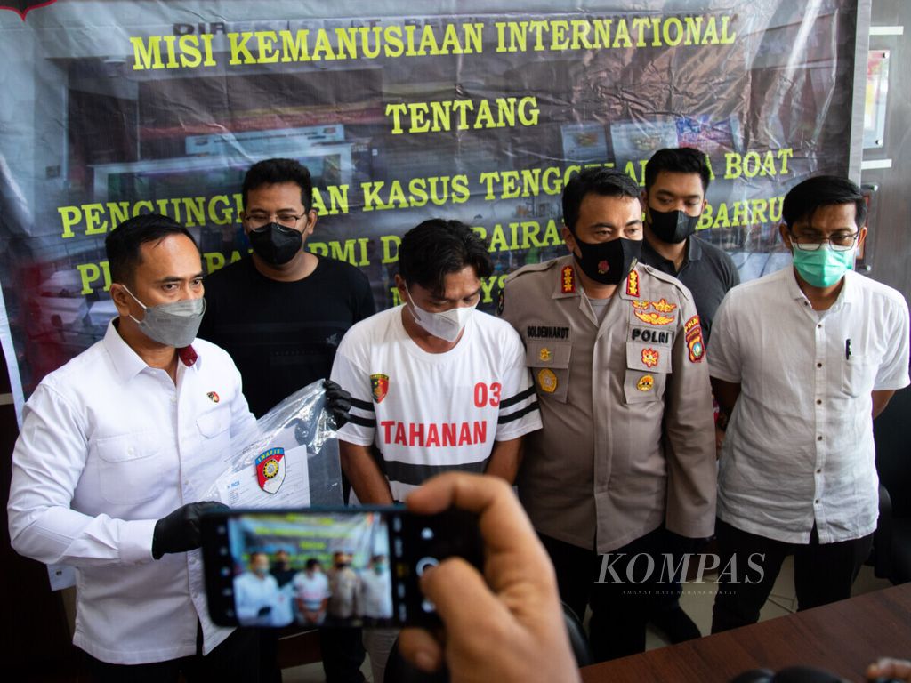 Polisi menghadirkan Susanto alias Acing (tengah) dalam rilis pers di Markas Polda Kepulauan Riau, Senin (3/1/2022). Tersangka Acing terlibat memberangkatkan 64 pekerja migran Indonesia ilegal yang tenggelam di perairan Johor, Malaysia, pada 15 Desember 2021.