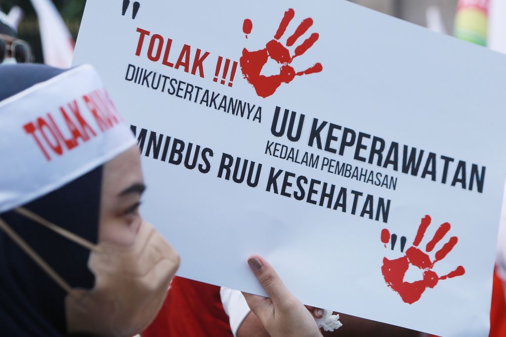 Tenaga kesehatan membawa poster saat demonstrasi menolak RUU Kesehatan <i>omnibus law</i> di depan Gedung DPR, Jakarta, Senin (28/11/2022). 