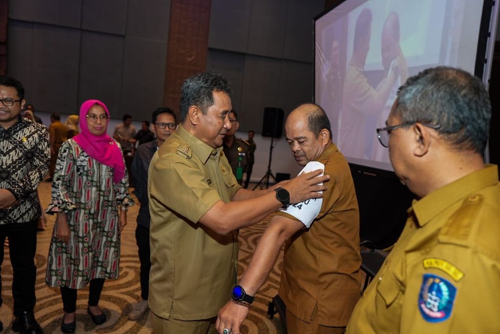 Penjabat Gubernur Sulsel Bahtiar Baharuddin menyematkan atribut di lengan petugas kesehatan, Selasa (30/1/2024). Petugas kesehatan ini akan diterjunkan di TPS saat penghitungan nanti.