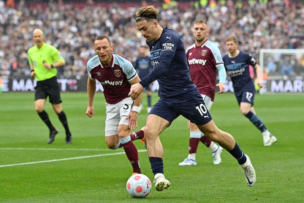 Pemain Manchester City Jack Grealish menggiring bola dengan dibayangi para pemain West Ham pada laga Liga Inggris di Stadion London, Minggu (15/5/2022). Laga berakhir imbang 2-2. 
