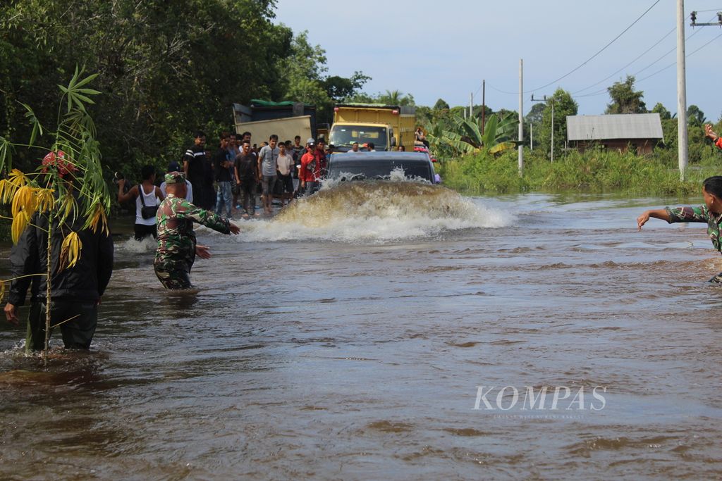 Warga Desa Lembeng, Kecamatan Dusun Selatan, Kabupaten Barito Selatan, Kalteng, membantu pikap yang ingin melintas di titik banjir jalur Trans-Kalimantan yang menghubungkan tiga provinsi, Kamis (25/1/2024). 