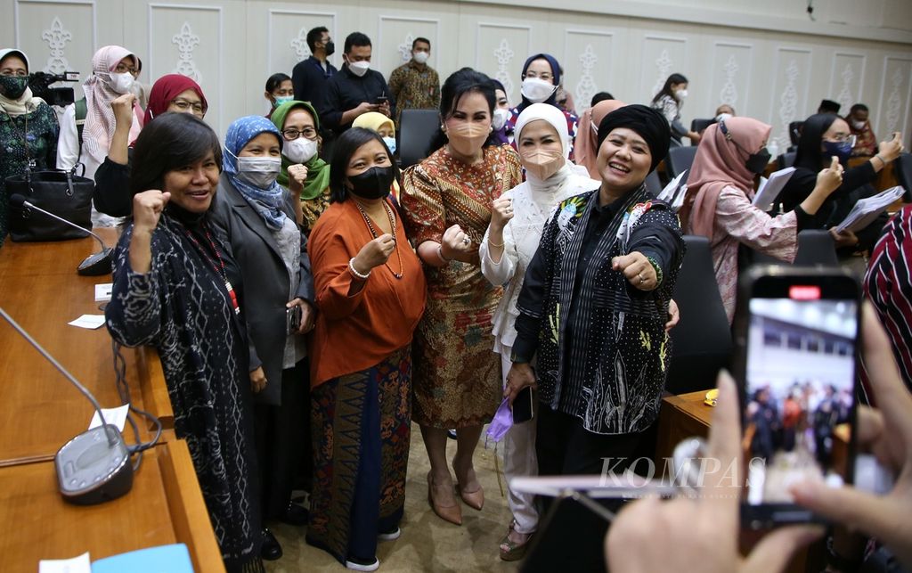 Para aktivis perempuan berfoto bersama anggota Badan Legislasi DPR seusai rapat pleno pengambilan keputusan tingkat satu atas hasil pembahasan Rancangan Undang-Undang Tindak Pidana Kekerasan Seksual dengan Badan Legislasi DPR di Kompleks Parlemen, Senayan, Jakarta, Rabu (6/4/2022).  