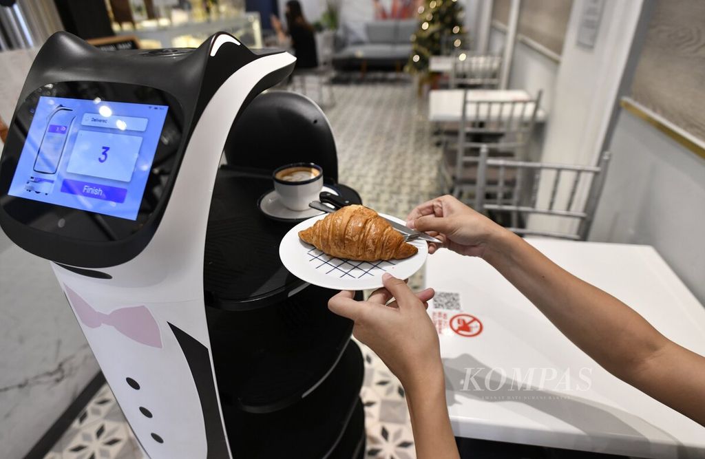 Pengunjung mengambil makanan dan minuman yang diantarkan oleh robot pelayan bernama Kitty di kafe Rasa Koffie, Jakarta, Sabtu (15/1/2022). 