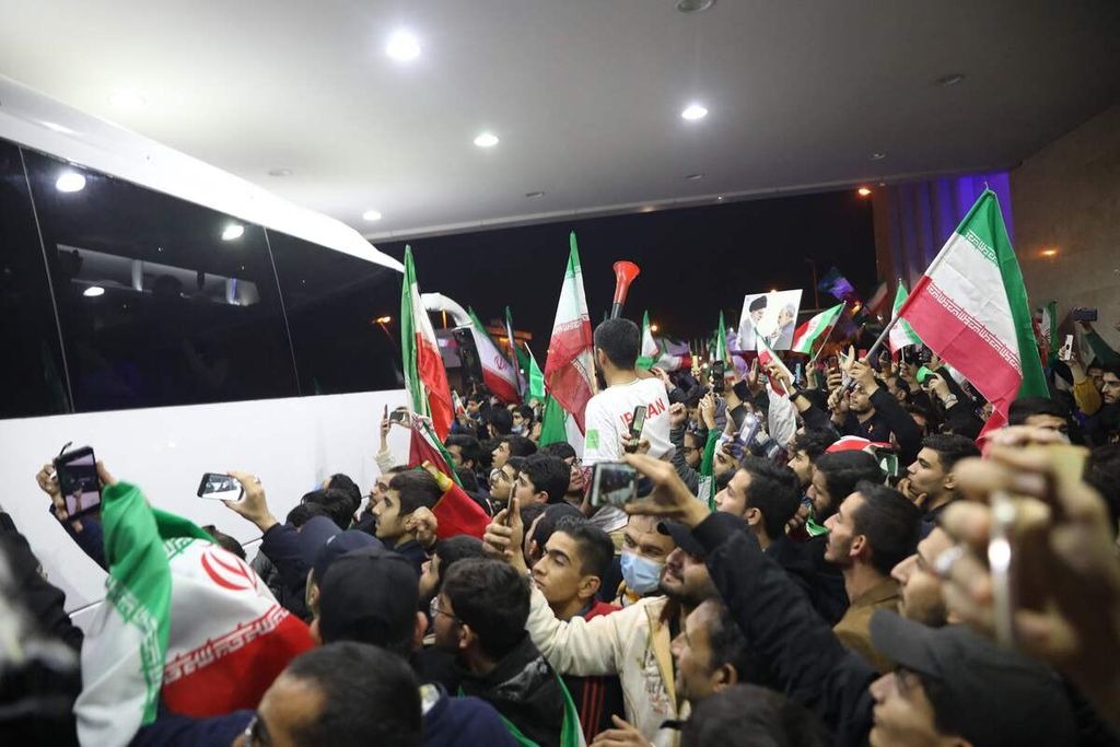 Para pendukung Iran mengibarkan bendera menyambut kedatangan tim nasional Iran di Bandara Imam Khomeini, Teheran, Iran, Kamis (1/12/2022).  Timnas Iran kembali ke Teheran seusai mengikuti Piala Dunia Qatar 2022. Mereka gagal lolos setelah dikalahkan Amerika Serikat, 0-1, pada laga terakhir Grup B, dua hari sebelumnya.