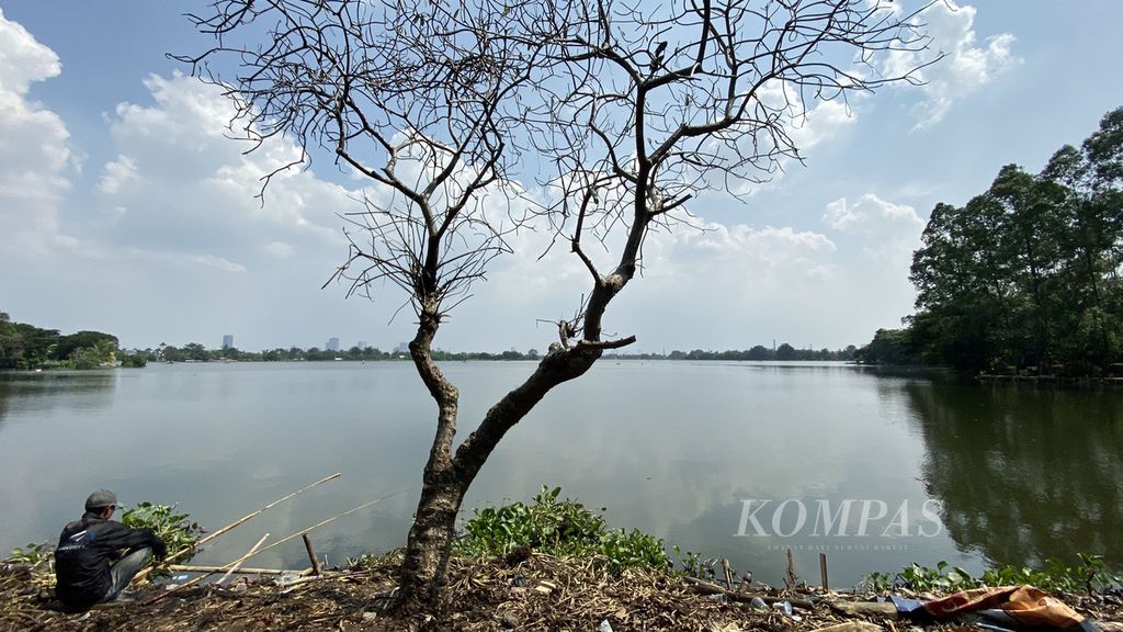 Warga memancing ikan di samping pohon yang mengering di Situ Cipondoh, Kota Tangerang, Banten, Kamis (7/5/2020).