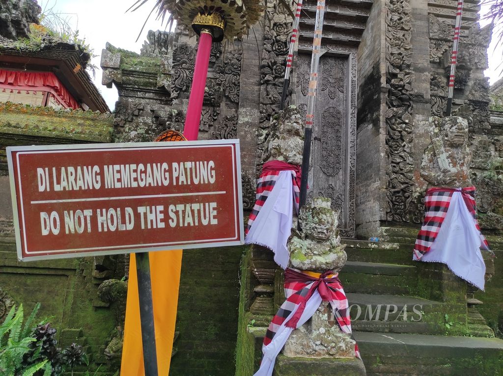 Sebuah papan larangan untuk menjaga kesucian patung yang berada di pura kawasan Desa Adat Penglipuran, Kabupaten Bangli, Bali, Selasa (28/6/2022). Bagi mayoritas wisatawan, berfoto dengan latar belakang pura Desa Penglipuran adalah salah satu hal yang wajib dilakukan ketika mengunjungi lokasi wisata adat itu.