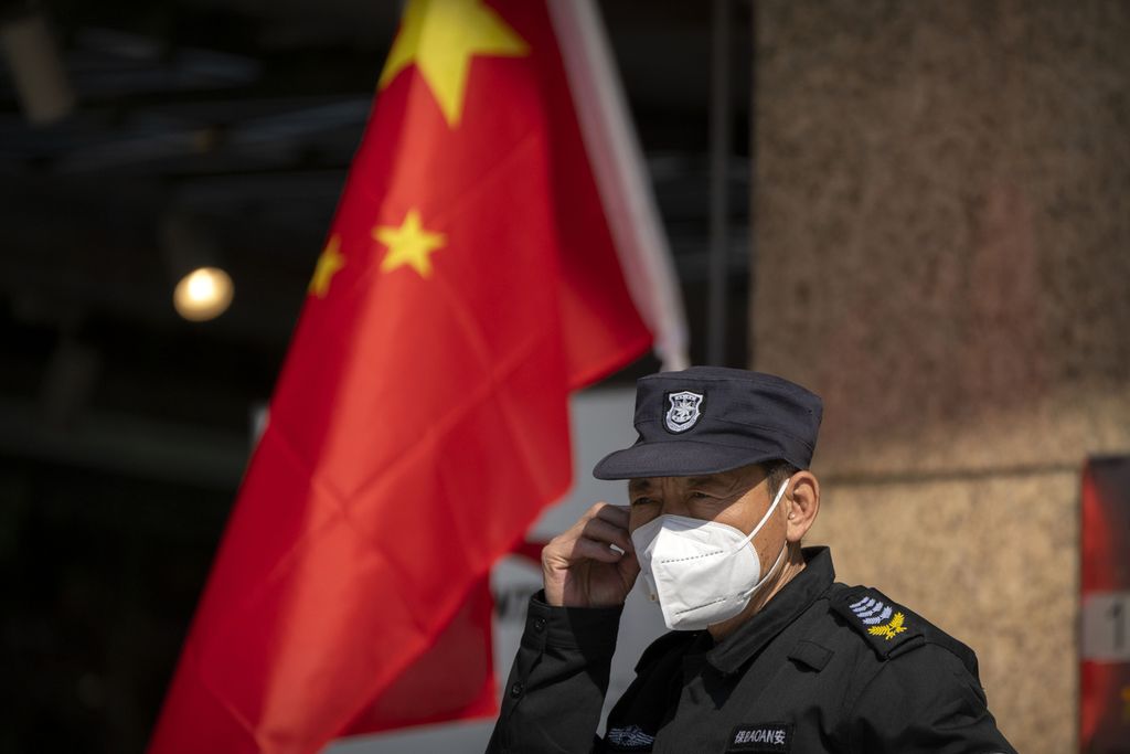 Petugas keamanan mengenakan masker saat berdiri di dekat bendera China di depan toko di area perbelanjaan di Beijing, 6 Oktober 2022. 