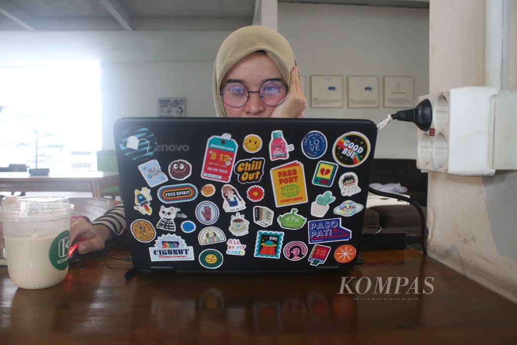 Anggun (32) bekerja secara daring dari salah satu kafe di Kota Bandung, Jawa Barat, Jumat (10/3/2023). Selama pandemi, semua pekerjaannya dilakukan secara daring sehingga Anggun bekerja dari mana saja.