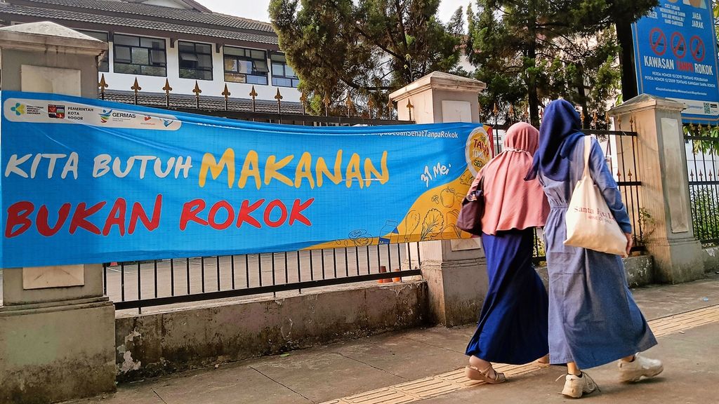 Warga melintasi jalur pedestarian di sekitar Jalan Kapten Muslihat, Kota Bogor, Jawa Barat, Kamis (29/6/2023). Di jalur pedestarian itu terpajang plang kawasan tanpa rokok dan spanduk kampanye antirokok.