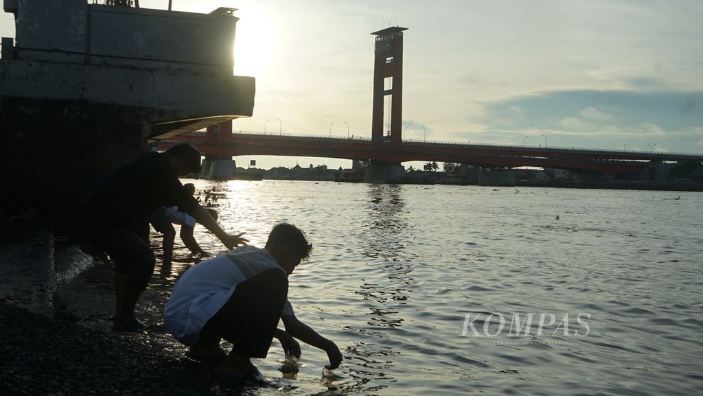 Beberapa warga sedang mengambil wudu di tepian Sungai Musi Palembang, Senin (2/5/2022). Rasa rindu memuncak bagi sejumlah warga Palembang karena dalam dua tahun terakhir tidak bisa mejalankan rutinitas ini.