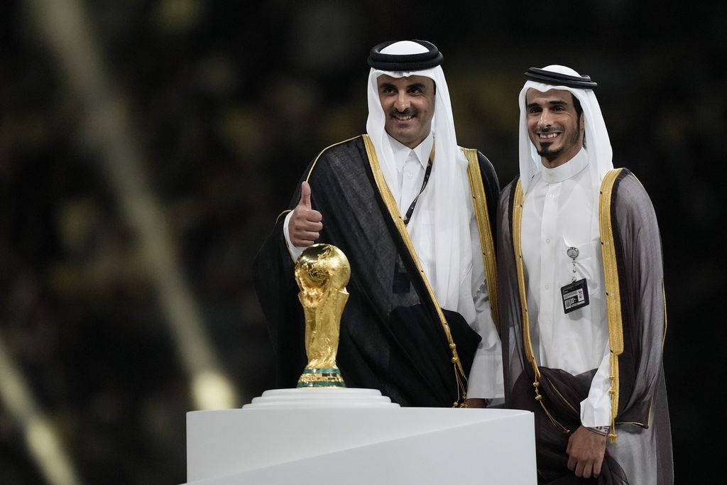Emir Qatar, Sheikh Tamim bin Hamad al-Thani (kiri), saat berdiri di podium selaku tuan rumah menjelang upacara pemberian Piala Dunia 2022 seusai final Argentina melawan Perancis yang berakhir dengan kemenangan Argentina di Lusail Stadium di Lusail, Qatar, Minggu (18/12/2022). 