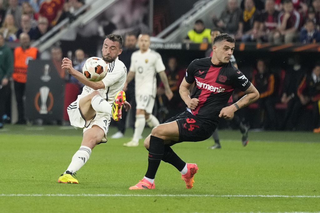 Pemain Bayer Leverkusen Granit Xhaka dan pemain AS Roma Bryan Cristante berebut bola dalam pertandingan semifinal kedua Liga Europa antara Bayer Leverkusen dan AS Roma di Stadion Bay Arena, Leverkusen, Jerman, Jumat (10/5/2024) dini hari WIB. 