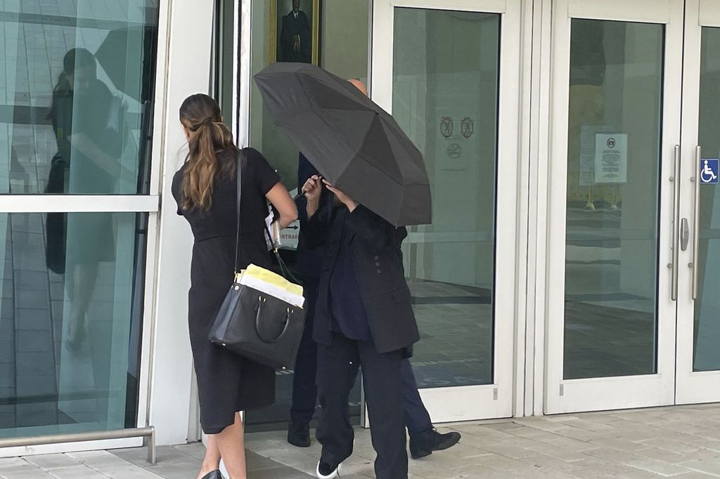 Perancang Nancy Gonzalez bersembunyi di balik payung dan pengacaranya Andrea Lopez (kanan) kala tiba di Pengadilan Miami, Florida, Senin (22/4/2024).