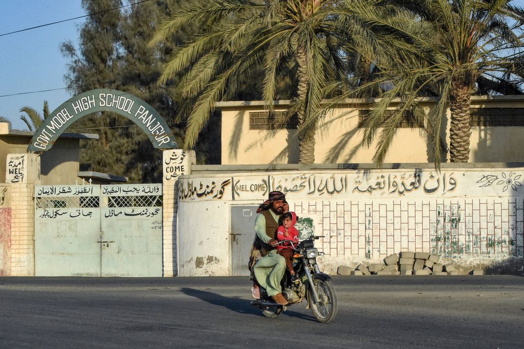 Pengendara sepeda motor melewati sebuah sekolah menengah di Distrik Panjgur, Provinsi Baluchistan, Pakistan, tempat para korban serangan udara Iran dipindahkan, Rabu (17/1/2024). 