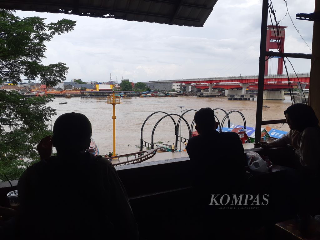 Sejumlah pelanggan di kedai kopi sedang menikmati pemandangan sore Sungai Musi dan Jembatan Ampera di lantai III, Pasar 16 Ilir Palembang, Sumatera Selatan, Kamis (14/6/2023). Keberadaan kedai meningkatkan minat berwisata di pinggiran Sungai Musi.