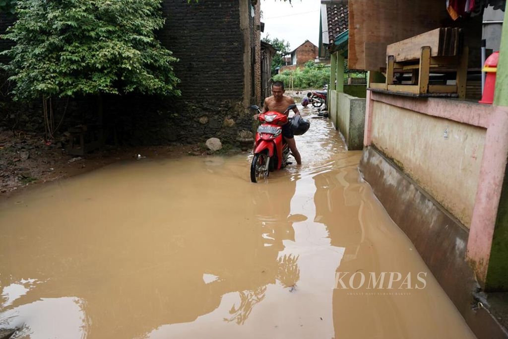 Seorang warga di Kelurahan Kalibalau Kencana, Kecamatan Kedamaian, Kota Bandar Lampung, Lampung, mendorong sepeda motor di tengah banjir, Rabu (23/5/2018). Banjir akibat luapan Sungai Way Balau terjadi setelah hujan deras mengguyur daerah tersebut lebih dari 6 jam.